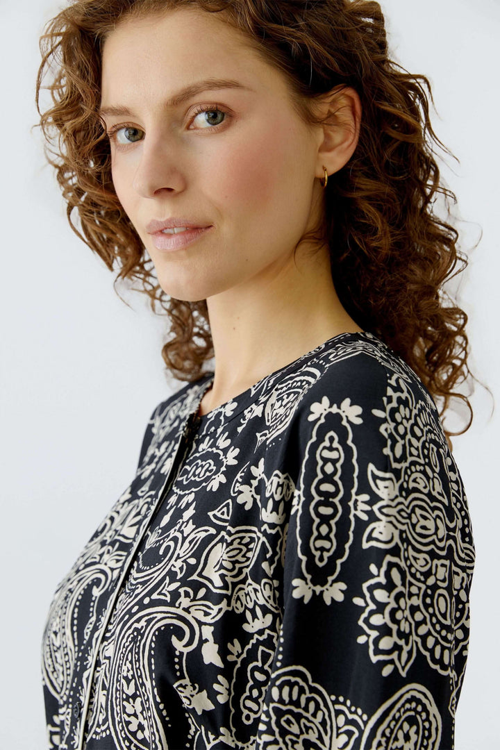 Femme portant une robe courte imprimé graphique bohème avec ceinture, vue de côté, coupe droite et féminine, adaptable pour diverses occasions.