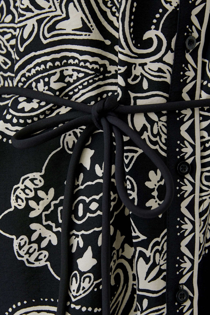 Détail de la ceinture sur robe courte imprimé graphique bohème, tissu noir et blanc à motifs élégants.
