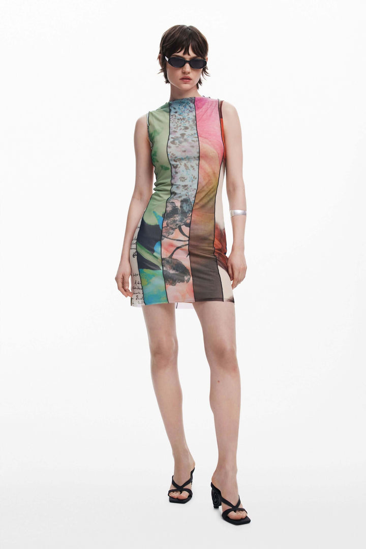 Robe courte ajustée en tulle avec des motifs colorés, col roulé et sans manches, portée par une mannequin avec des lunettes de soleil.