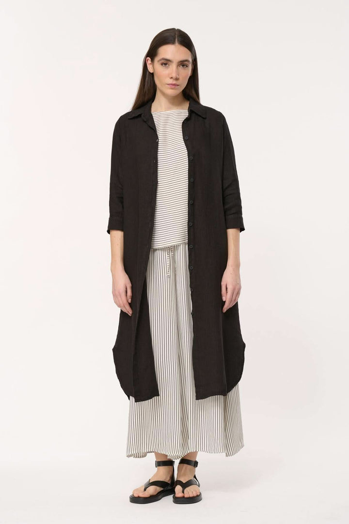 Robe longue Talicia en lin avec col chemise, manches longues et coupe fluide, portée avec un top rayé.