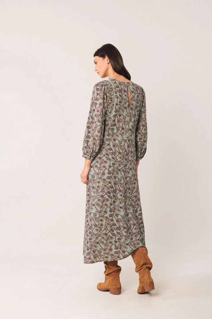 Robe longue à motif géométrique avec manches longues légèrement bouffantes, encolure ronde, portée avec des bottes en daim pour un look bohème chic.
