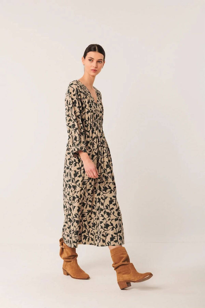 Robe longue fluide imprimé botanique avec décolleté en V, portée avec des bottes en cuir, style bohème.