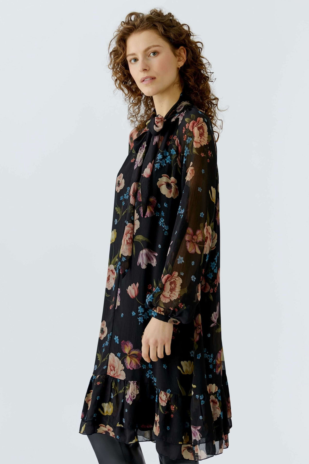 Robe midi fluide avec imprimé floral, coupe droite, et encolure à nouer, portée par une femme. Élégante, légère et vaporeuse.