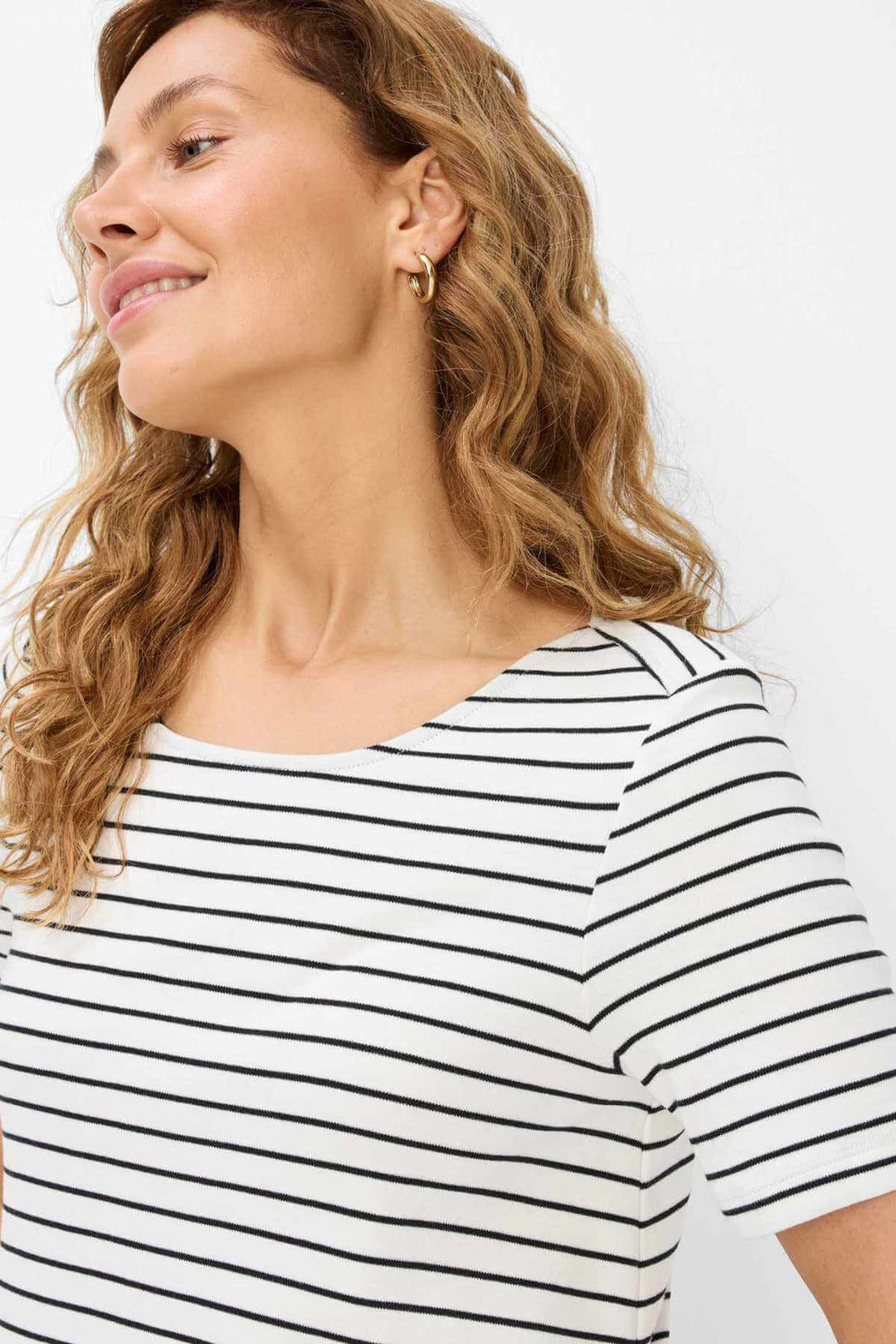 Femme souriante portant une robe rayée GRACE, à encolure ras du cou, ajoutant un style maritime.