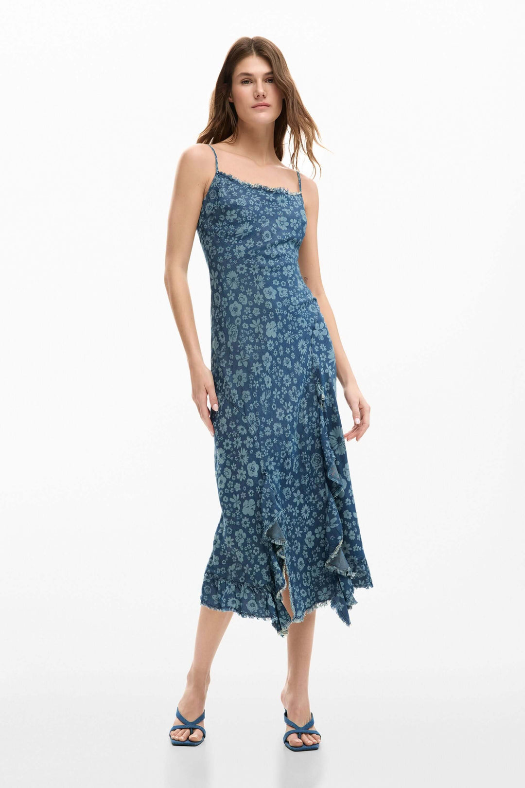 Femme portant une robe à volants en denim avec bretelles fines et volants asymétriques, idéale pour un style élégant et quotidien.