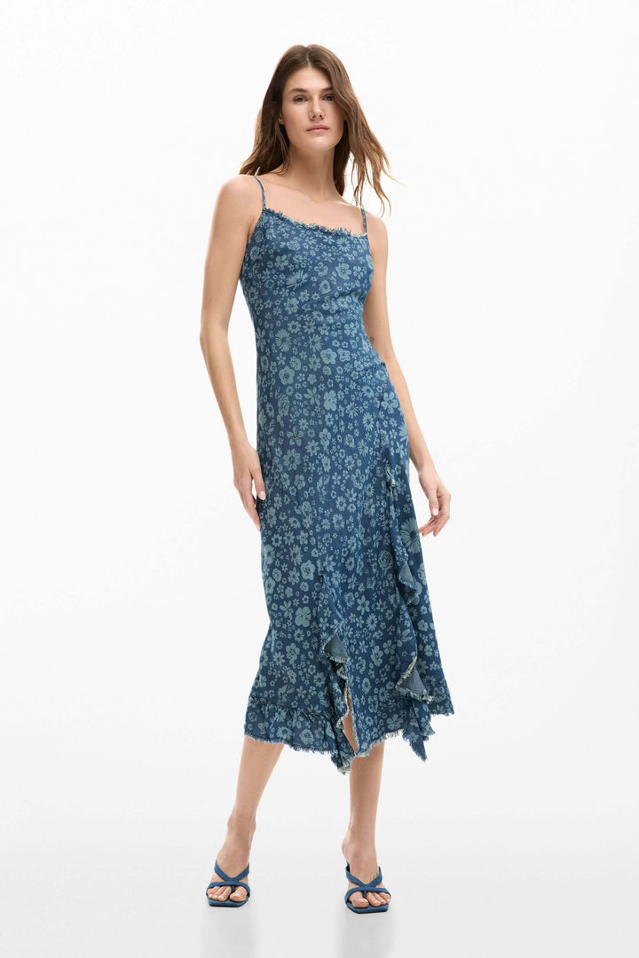 Femme portant une robe à volants en denim avec bretelles fines et volants asymétriques, idéale pour un style élégant et quotidien.