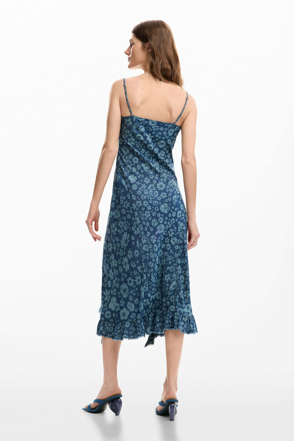 Femme portant une robe à volants en denim bleu à fines bretelles avec coupe ajustée et longueur midi, vue de dos.