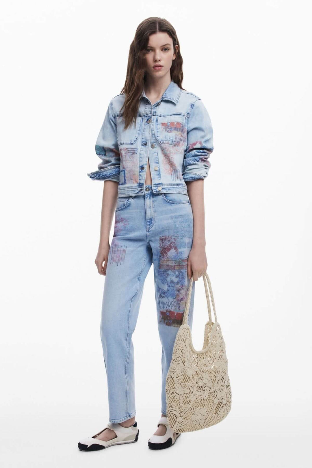 Femme en jean avec sac en crochet ajouré et chaussures noires, affichant un style décontracté et bohème.