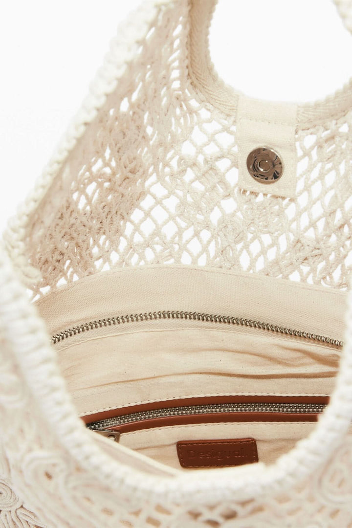 Intérieur du sac en crochet ajouré montrant sa doublure beige et ses poches zippées pour un rangement pratique.