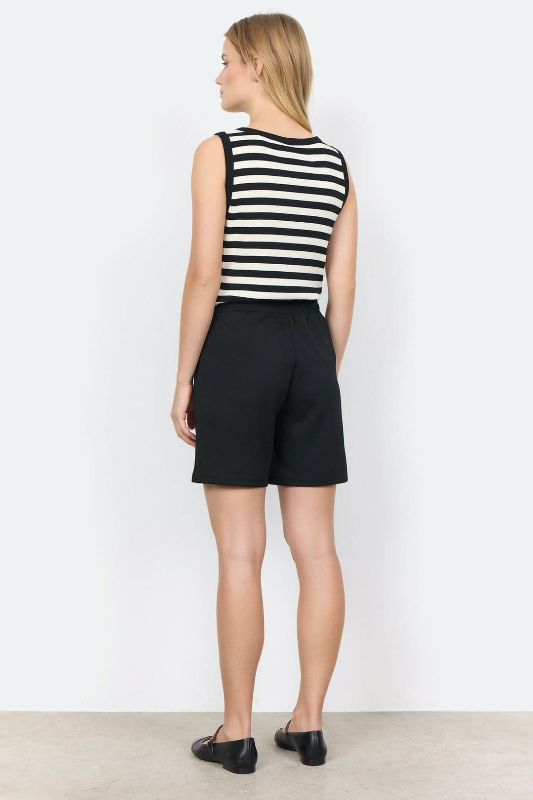 Short noir avec une bande élastique, porté par une femme vue de derrière, style décontracté.