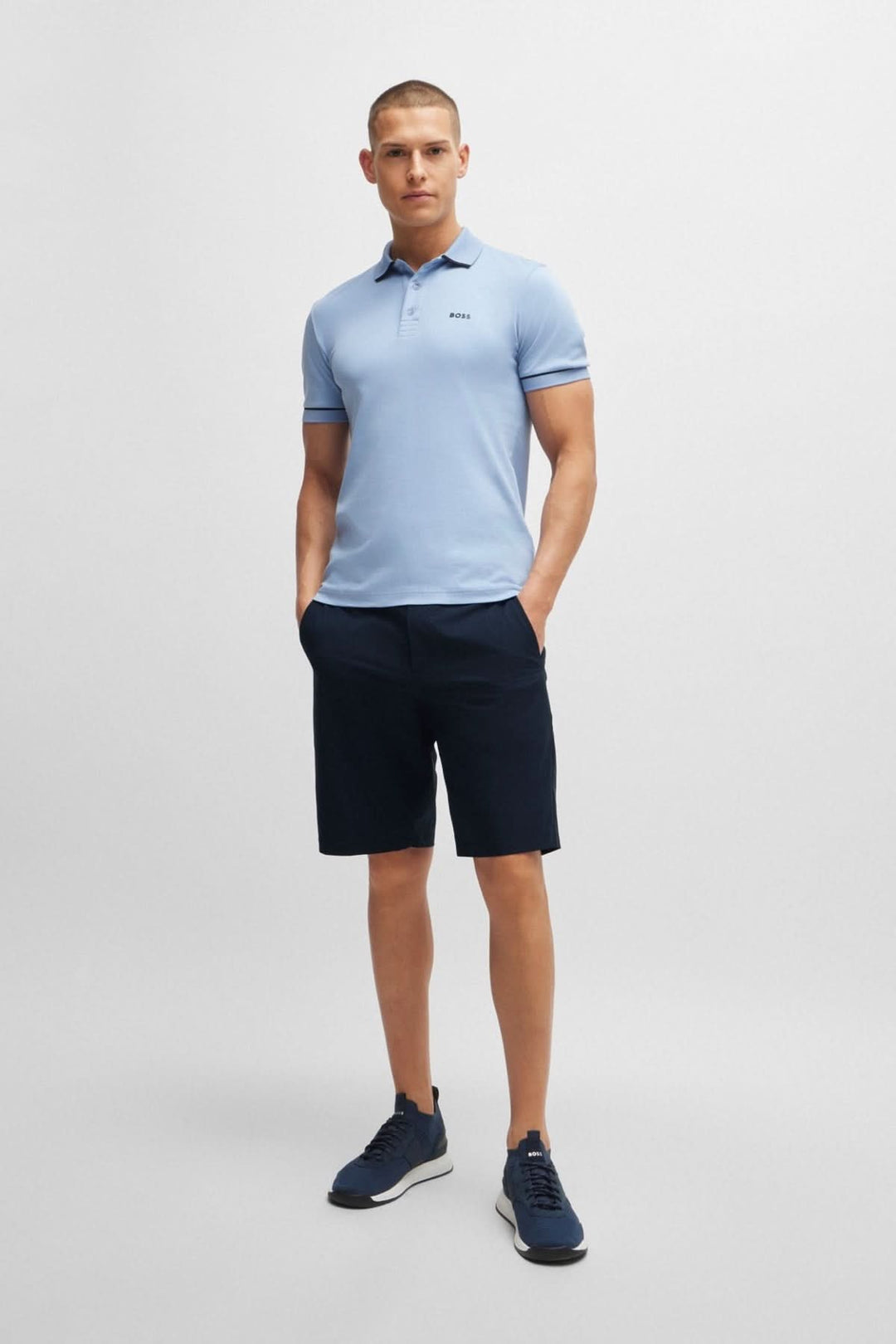 Homme portant un polo bleu clair et un short noir, parfait pour un look décontracté et sportif.
