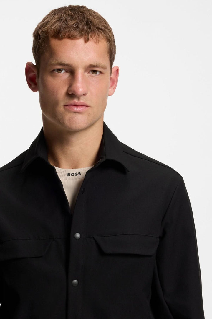 Homme portant une surchemise décontractée déperlante en gabardine BOSS, noire, avec col rabattable et boutons pressions.