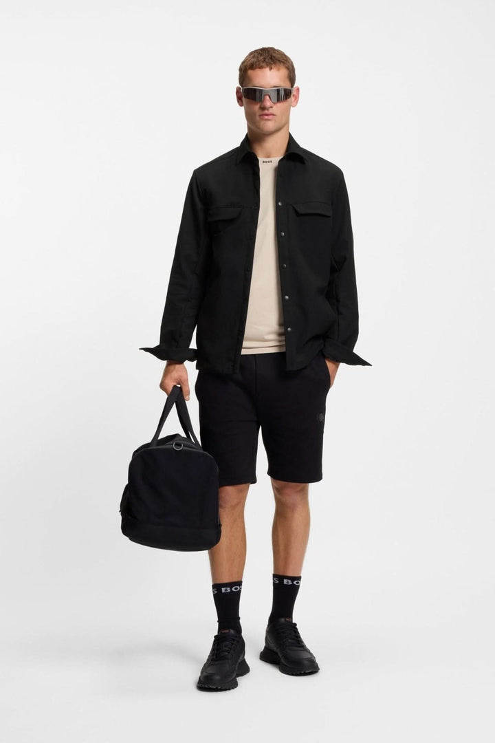 Homme portant une surchemise décontractée déperlante en gabardine BOSS, tenue moderne avec un sac à la main et des lunettes stylées.