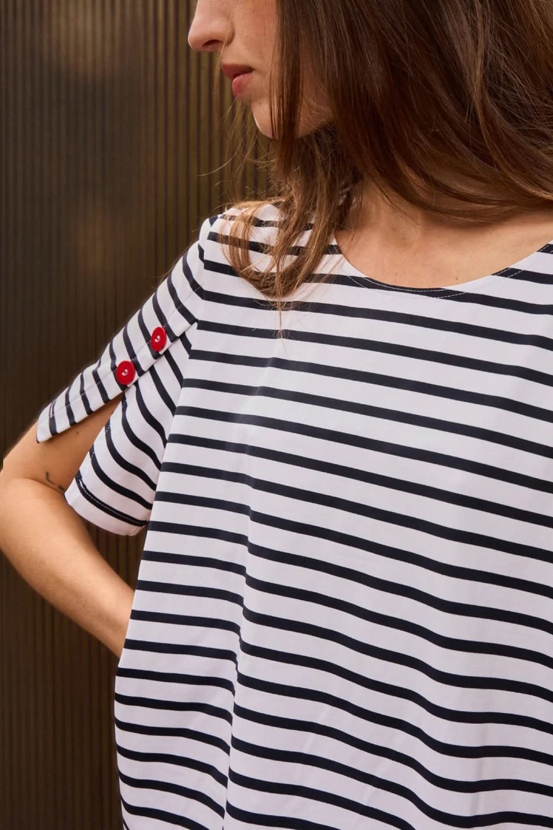 Femme portant un T-shirt CAP LEVI rayé avec boutons décoratifs sur manches courtes, style marin moderne et féminin.