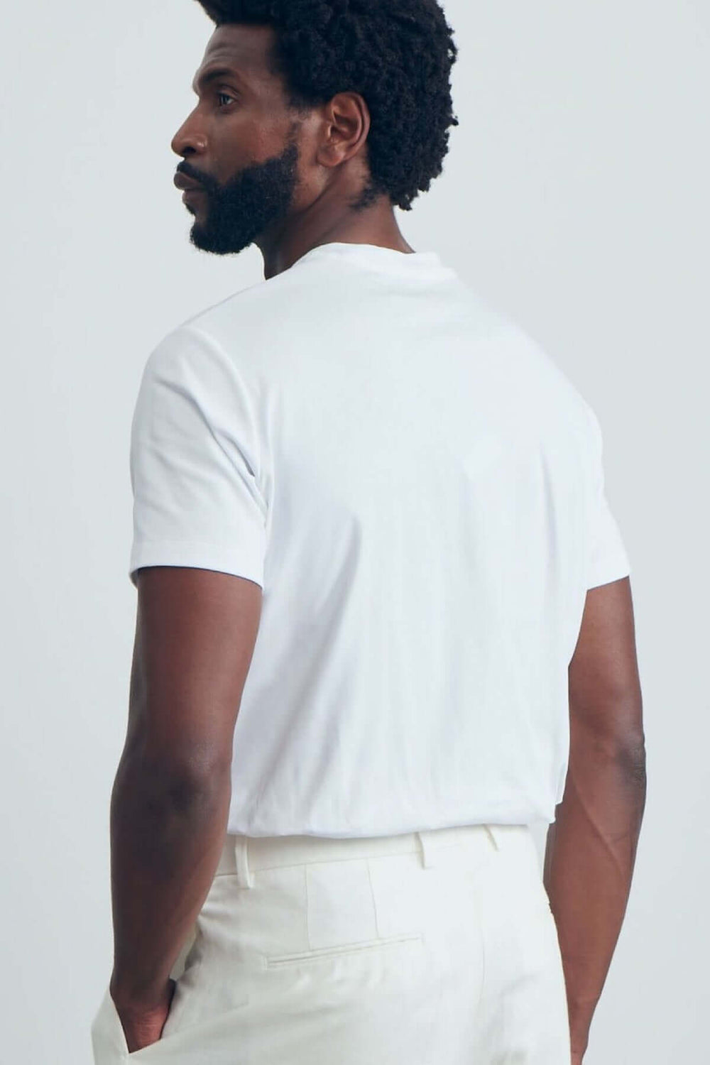 T-shirt moderne avec encolure ronde et coupe épurée, vu de dos, porté avec un pantalon clair.
