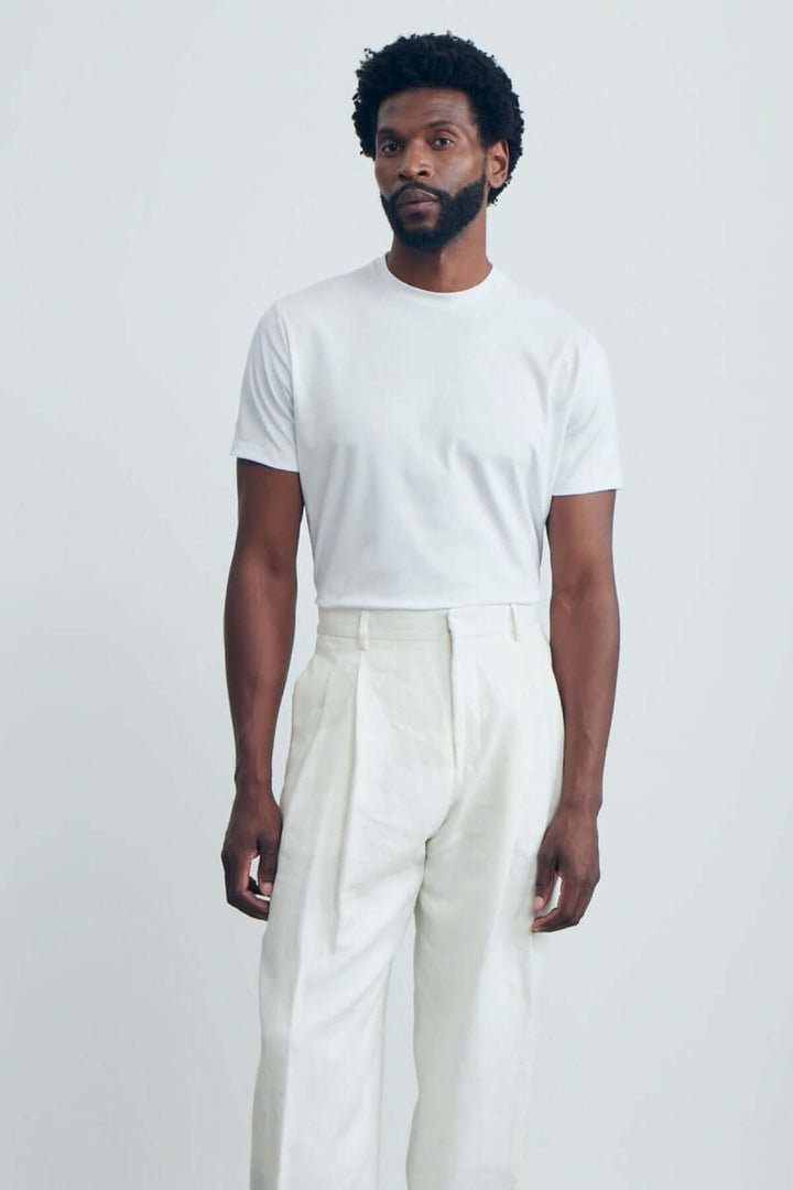 Homme portant un t-shirt blanc moderne avec un pantalon clair, look décontracté élégant.