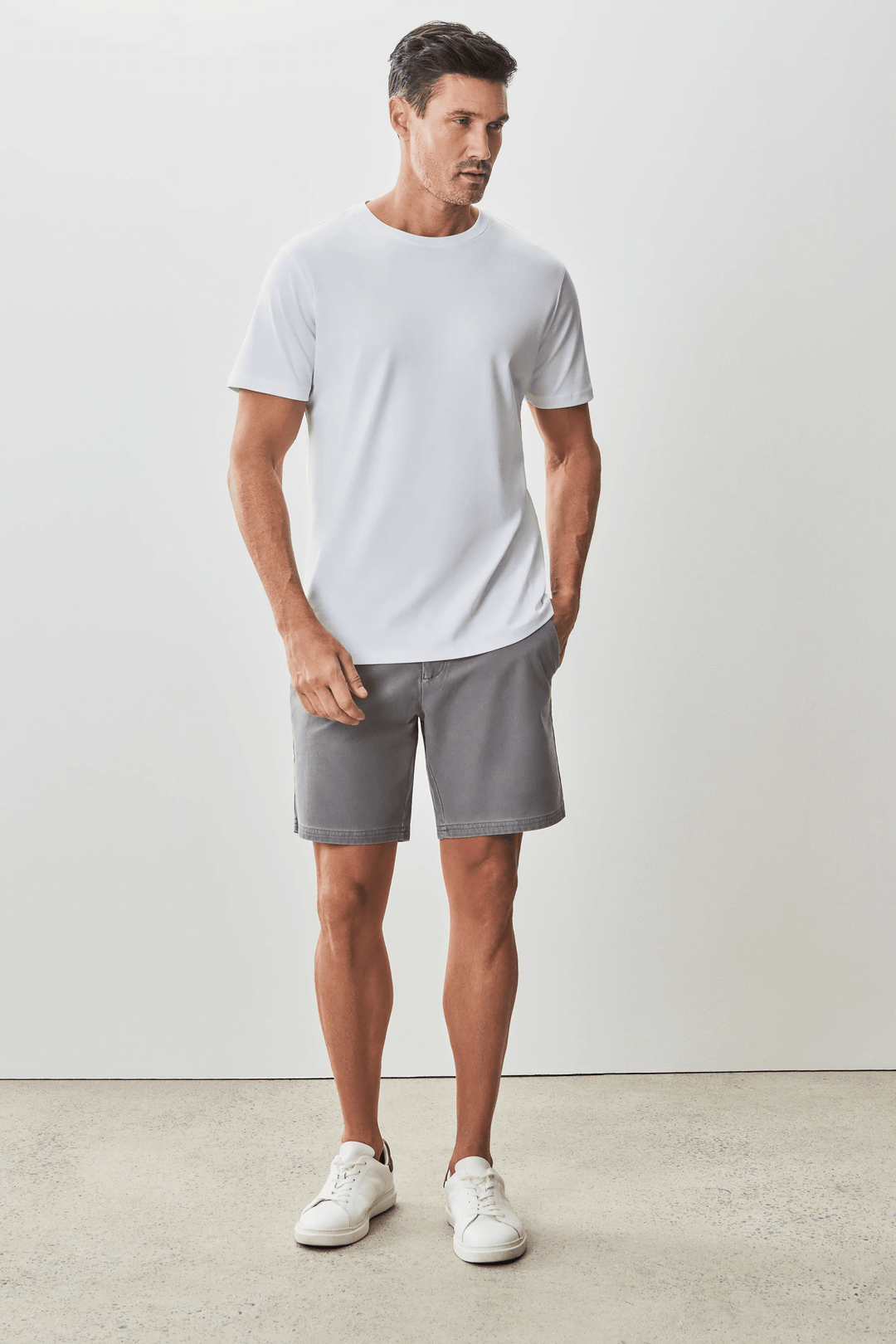 Homme portant un t-shirt blanc moderne et élégant avec un short gris, style minimaliste.