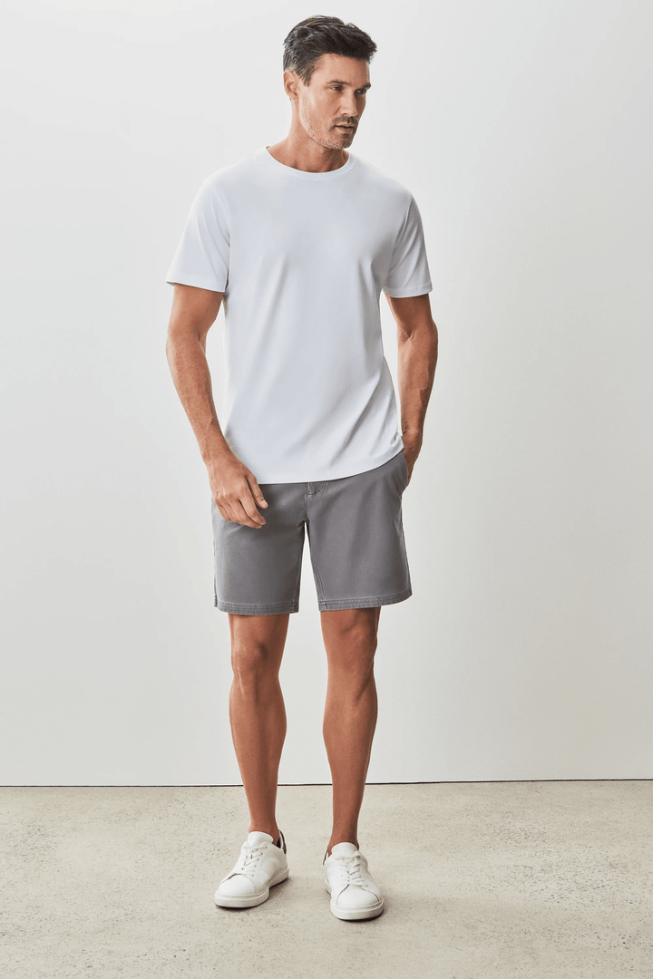 Homme portant un t-shirt blanc moderne et élégant avec un short gris, style minimaliste.