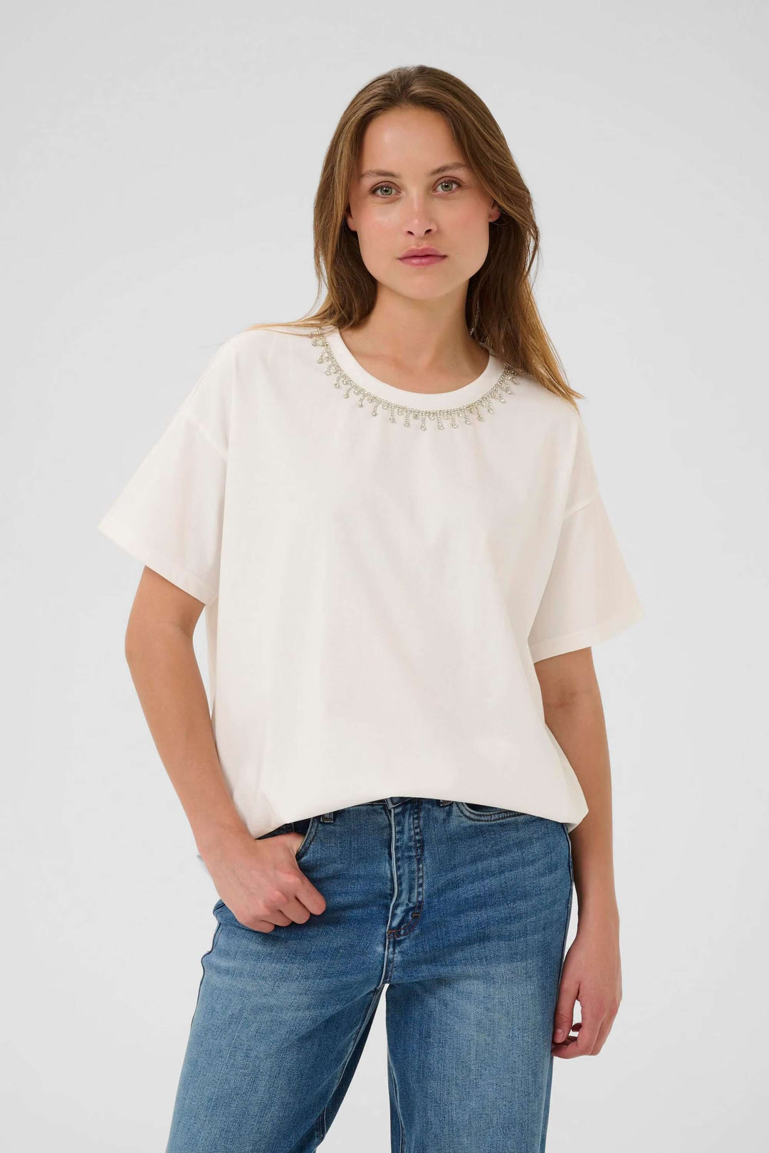 Femme portant un T-shirt blanc avec col rond et manches courtes, allié de confort et simplicité, idéal pour un style minimaliste élégant.
