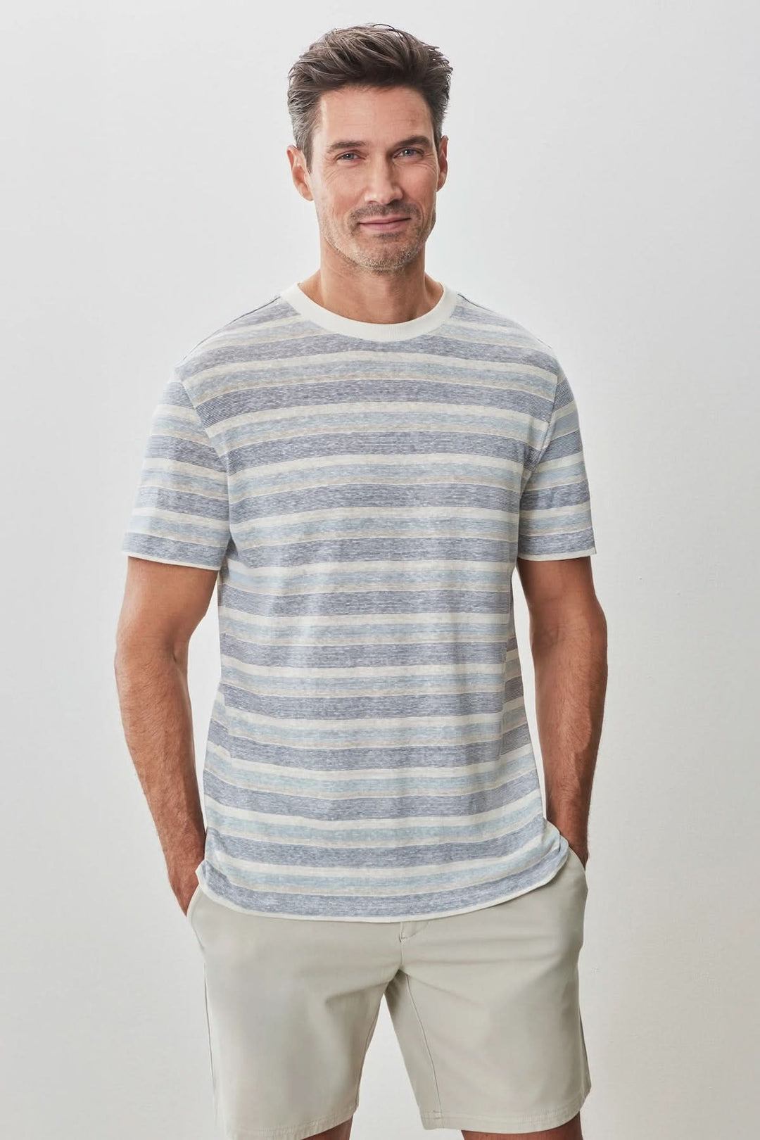Homme souriant portant un t-shirt à rayures estivales, manches courtes et encolure contrastante.
