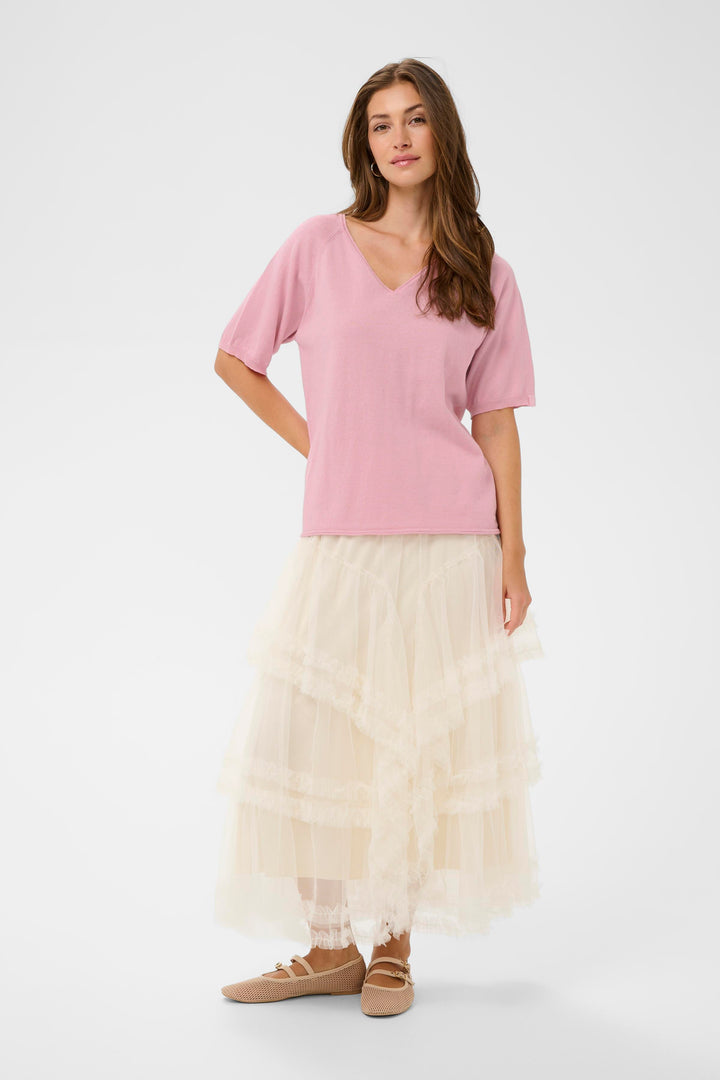 Femme portant le T-shirt Romane rose avec jupe longue, coupe décontractée et encolure en V, manches courtes amples pour un look simple.