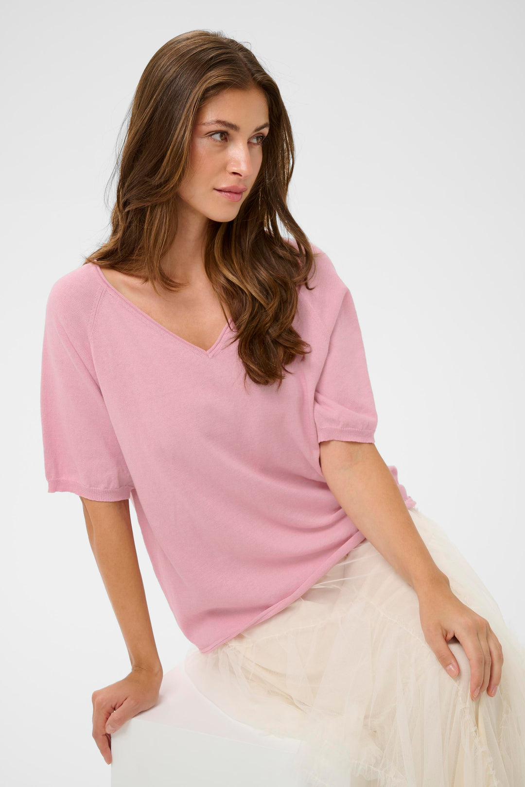 Femme portant le T-shirt Romane rose à encolure en V et manches amples, idéal pour un look décontracté et féminin.
