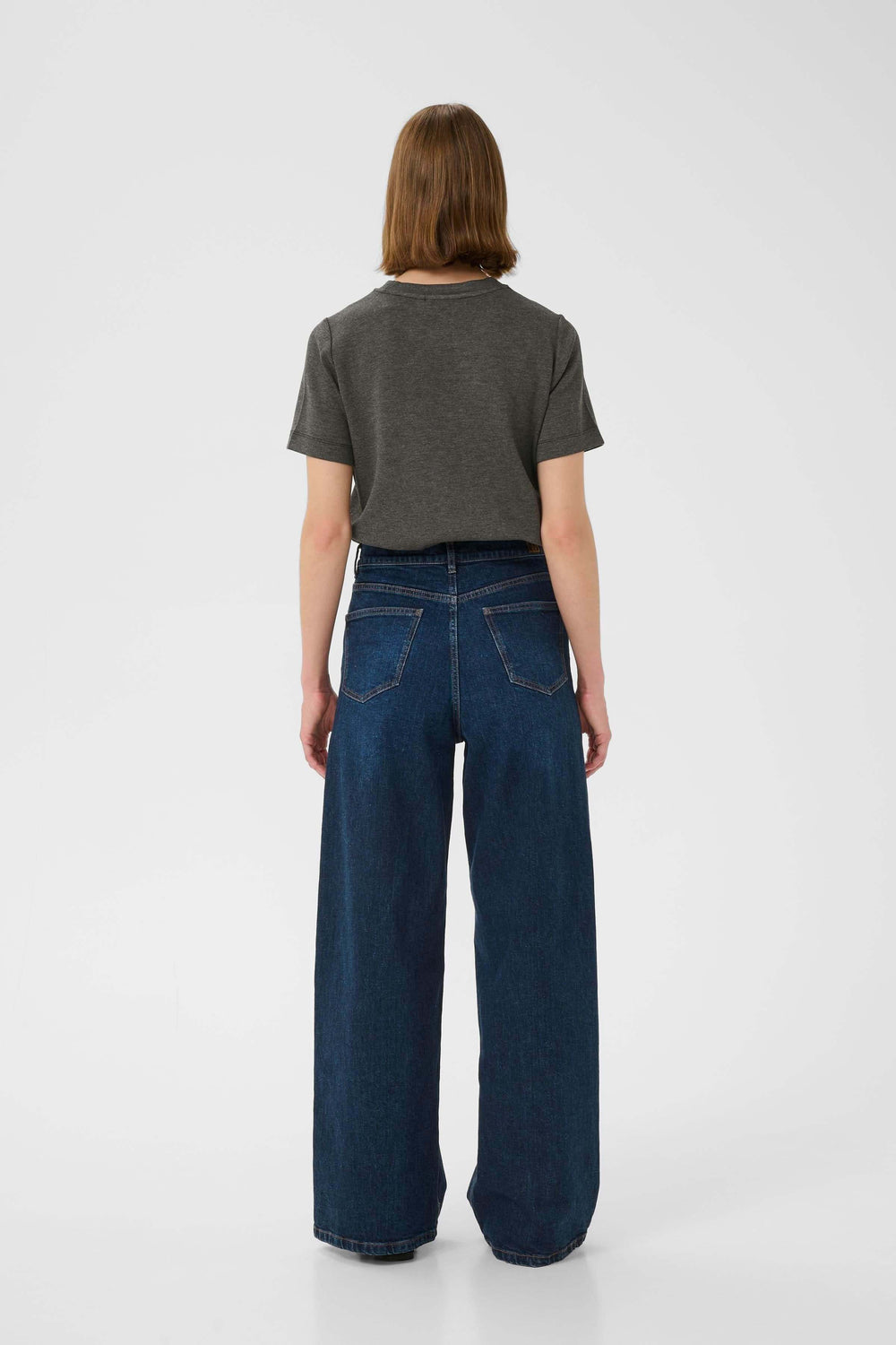 Femme de dos portant un t-shirt gris et un jean large, montrant un style décontracté et élégant.