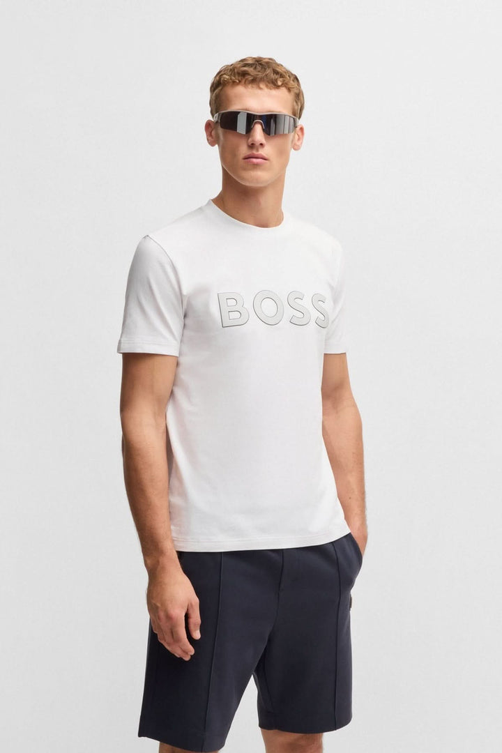 T-shirt blanc avec logo BOSS en relief, porté par un homme avec lunettes de soleil.