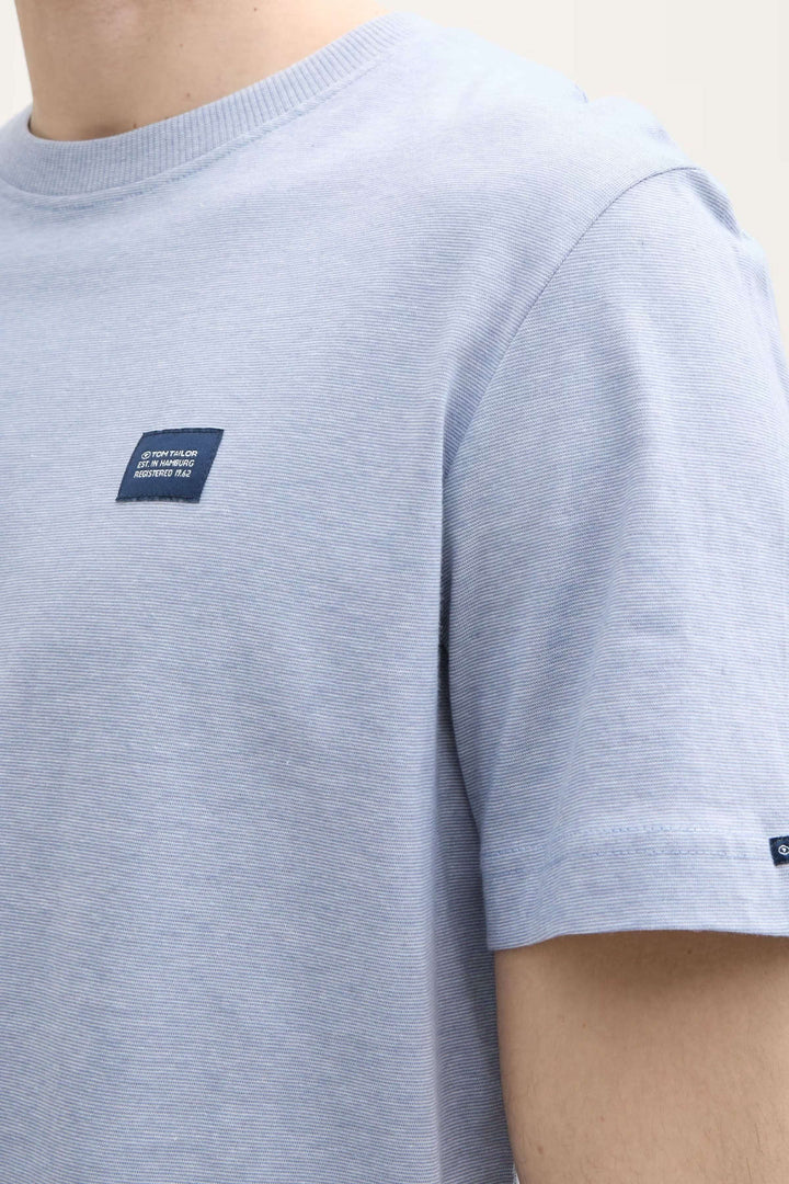 T-shirt bleu clair à manches courtes avec écusson brodé, style minimaliste et confortable.