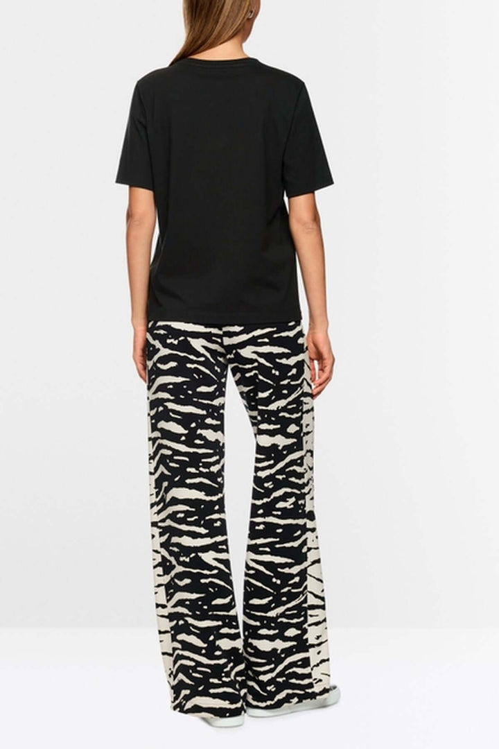 Vue arrière du T-shirt classique col rond noir, fabriqué en coton biologique, porté avec un pantalon imprimé animalier.