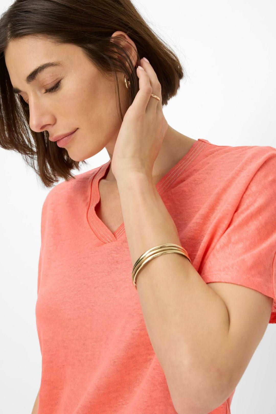 Femme portant un T-shirt col V CAELEN en rose, avec des épaules tombantes et un bracelet élégant.