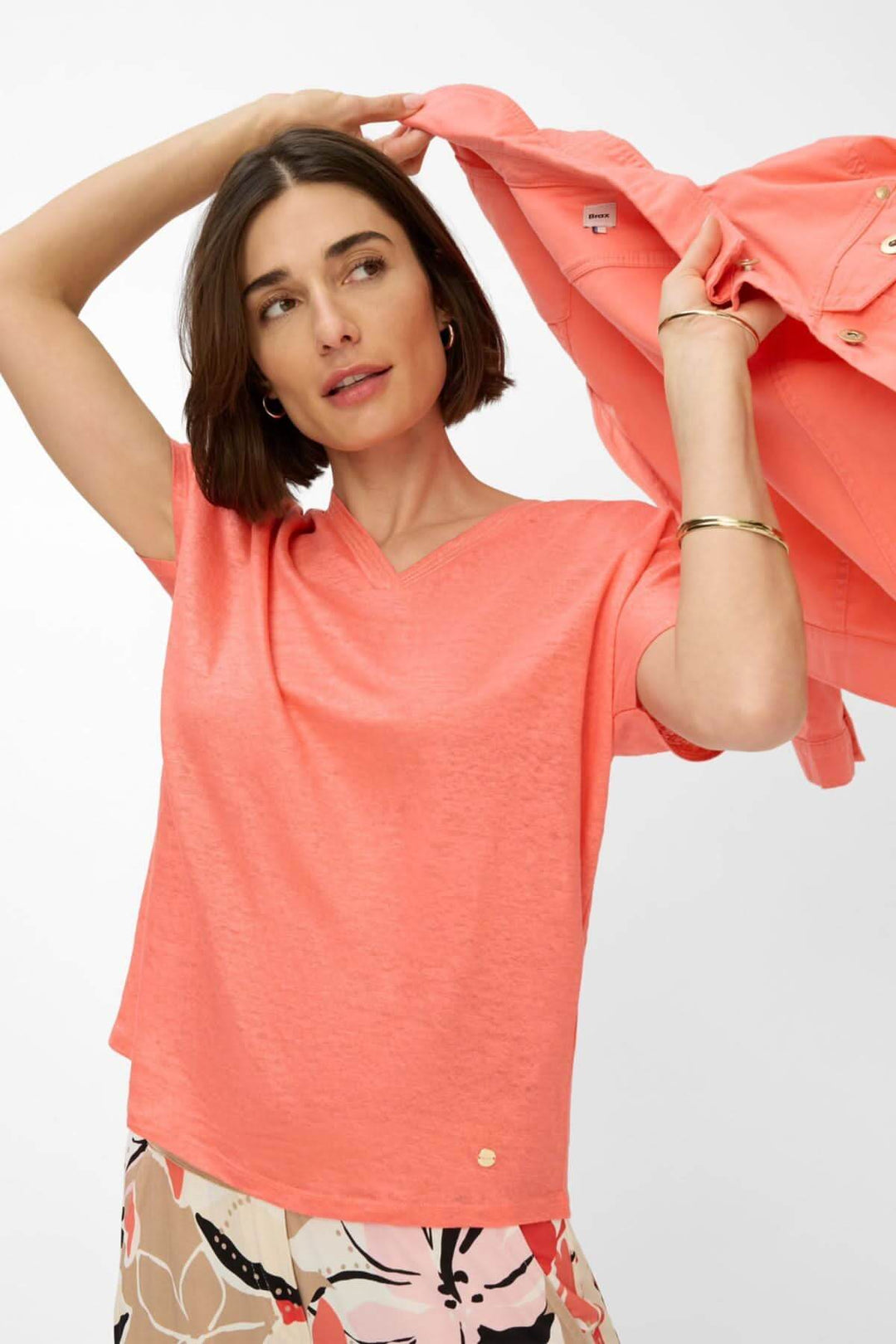 Femme portant un t-shirt col V CAELEN en corail, avec une chemise sur l&