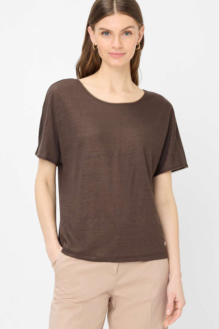 Femme portant un T-shirt col bateau Caelen marron avec manches courtes et coupe fluide, idéal pour un look décontracté et élégant.