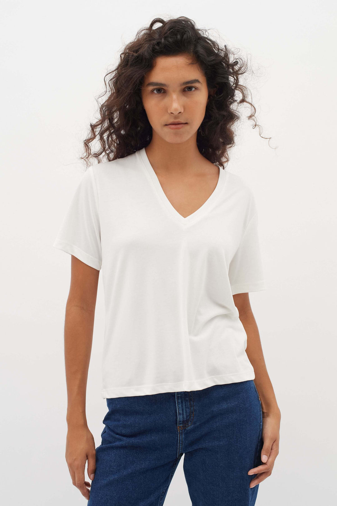 Femme portant un T-shirt col en V Liliana blanc avec une coupe droite et confortable, manches courtes et un style moderne.