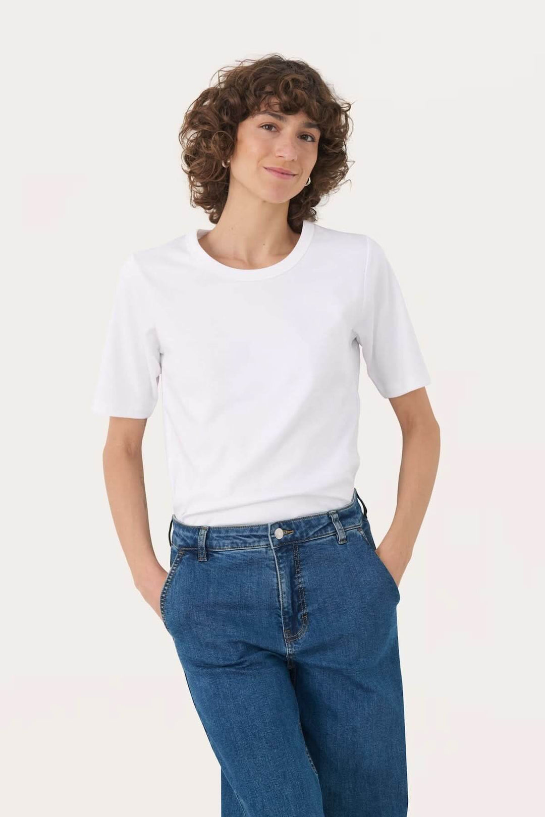 T-shirt à col rond blanc porté par une femme avec des jeans, style décontracté et confortable.