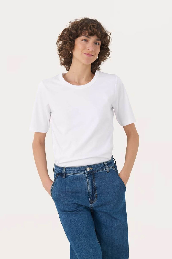 T-shirt à col rond blanc porté par une femme avec des jeans, style décontracté et confortable.