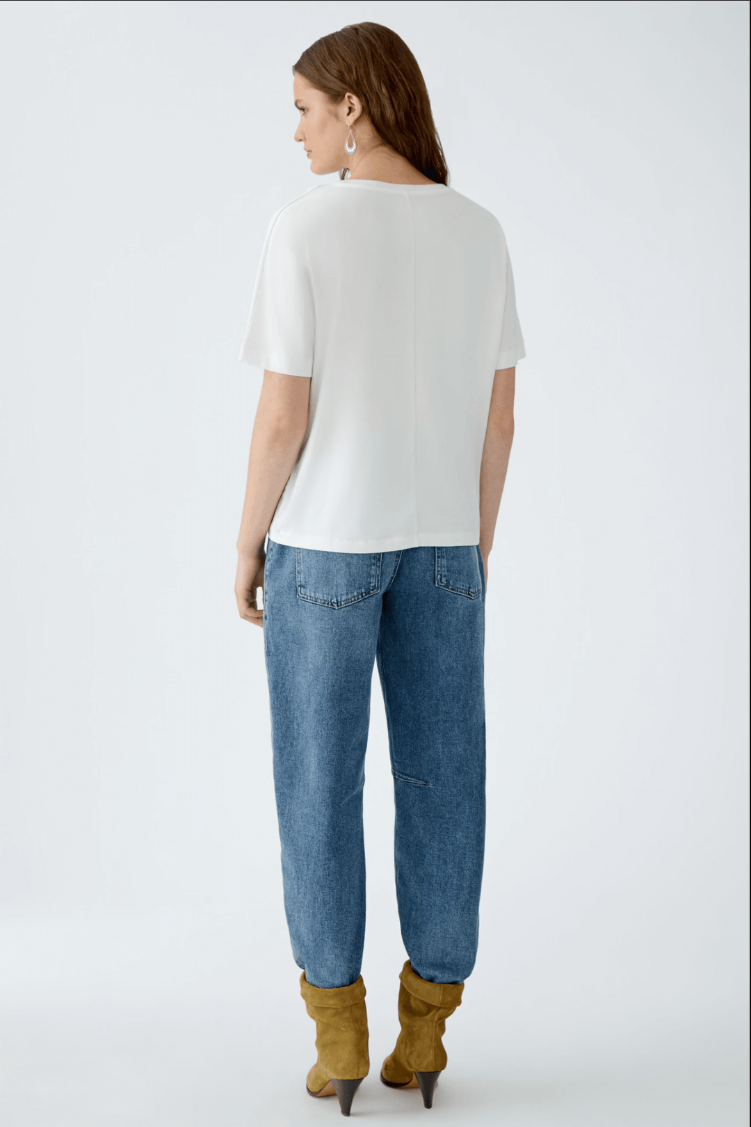 Femme vue de dos portant un t-shirt blanc et un jean bleu, associé à des bottines jaunes.