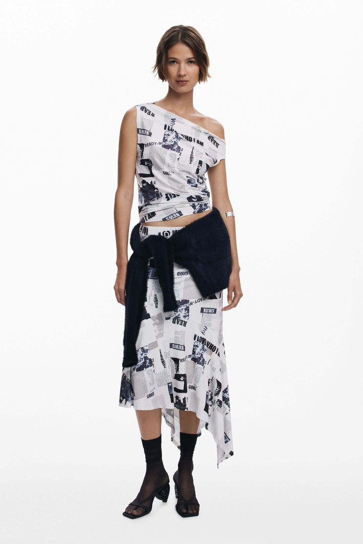 Femme portant un T-shirt drapé asymétrique à imprimé typographique, avec une jupe ou un pantalon taille haute, moderne et élégant.