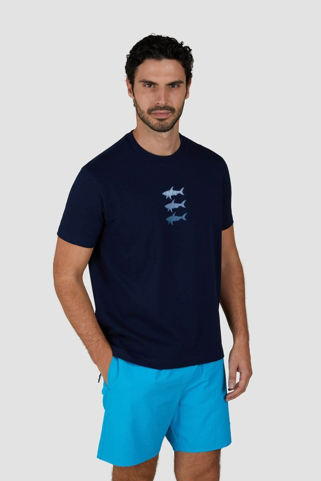 T-shirt en coton bleu marine avec imprimé de trois requins stylisés sur la poitrine, porté par un homme.