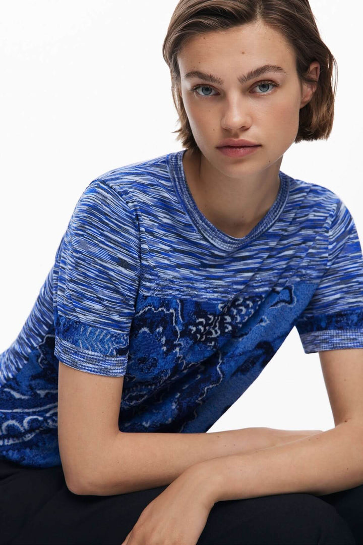 Femme portant un T-shirt en tricot à motif texturé façon carte topographique, coupe courte, manches courtes, en maille jacquard bleu.
