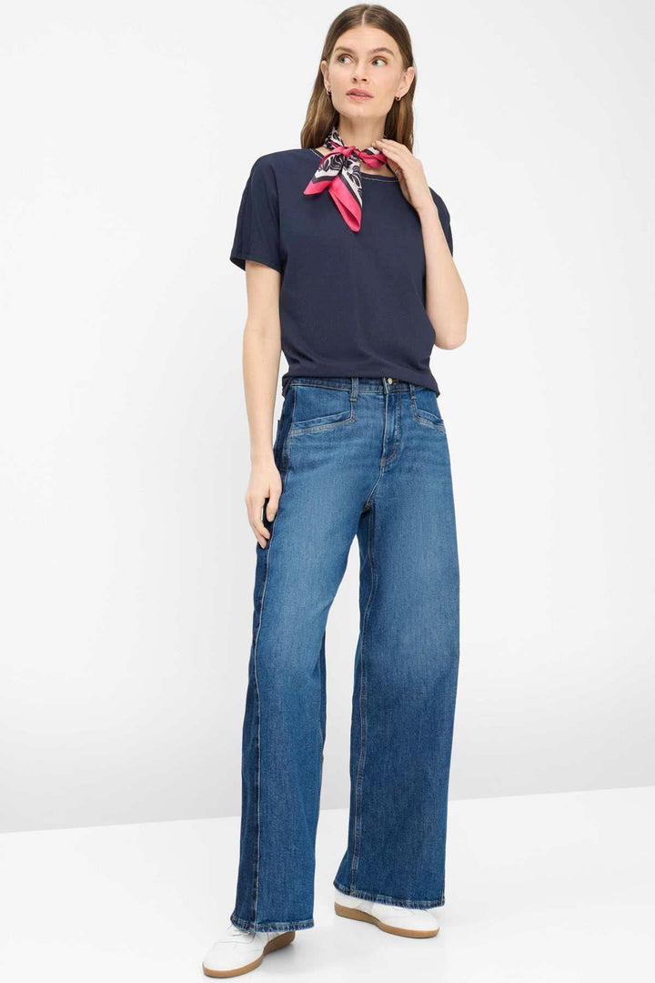 Femme portant un T-shirt encolure perlée Caelen avec des jeans évasés, illustrant l&