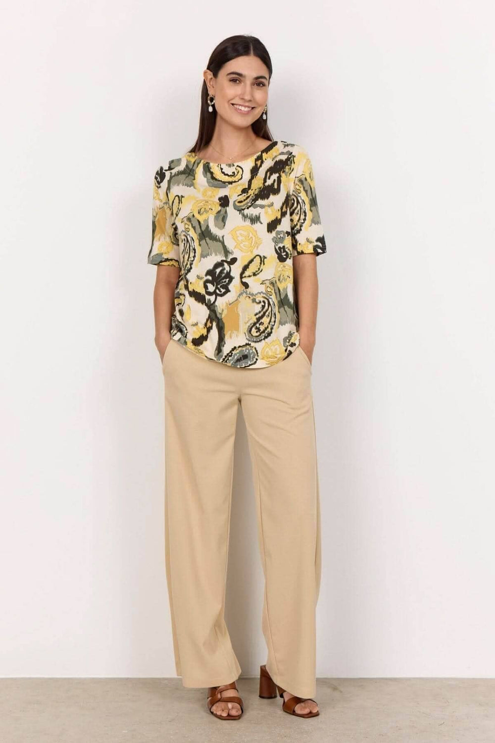 T-shirt imprimé abstrait avec encolure bateau, porté avec un pantalon clair pour un look élégant.