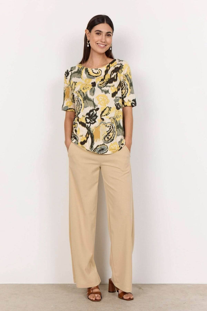 T-shirt imprimé abstrait avec encolure bateau, porté avec un pantalon clair pour un look élégant.