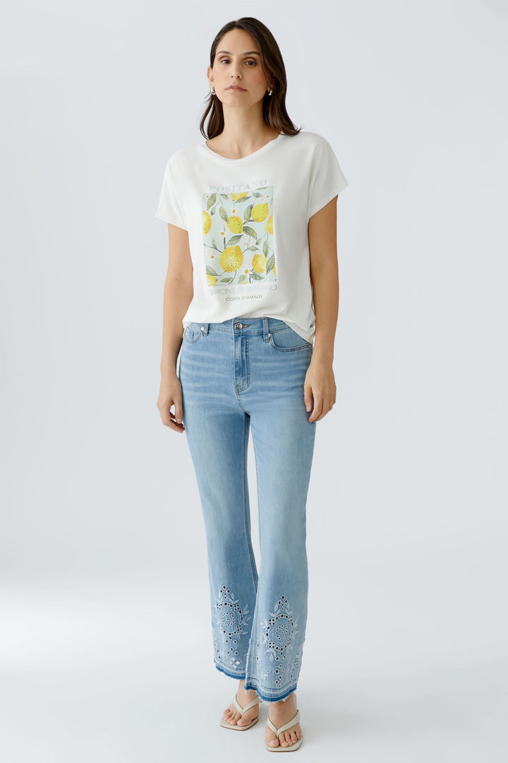 Femme portant un t-shirt imprimé à manches courtes avec motif graphique et jeans pour un look décontracté.