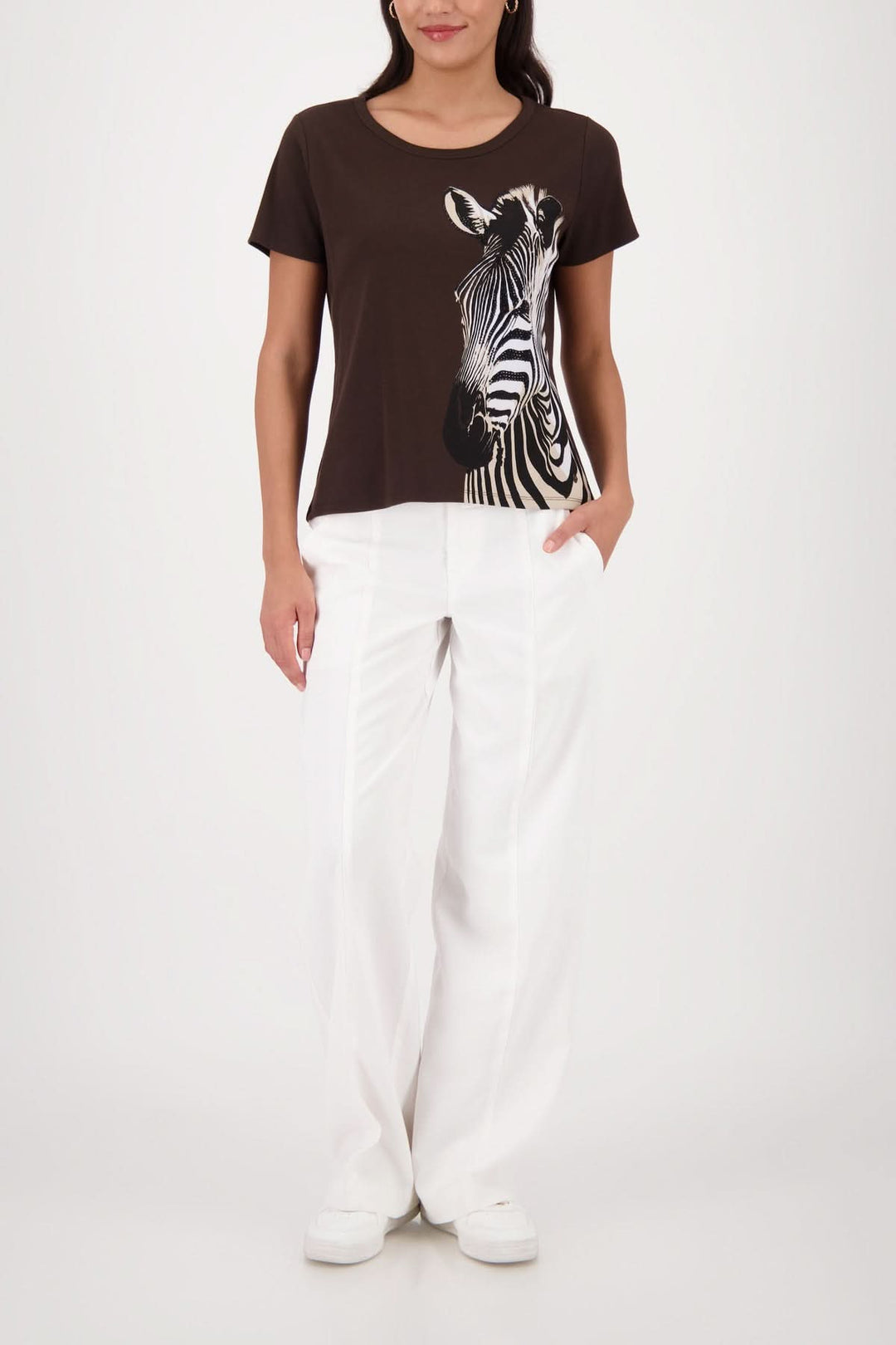 Femme portant un T-shirt imprimé zèbre avec une coupe simple et encolure arrondie, idéal pour un look moderne avec un pantalon blanc.