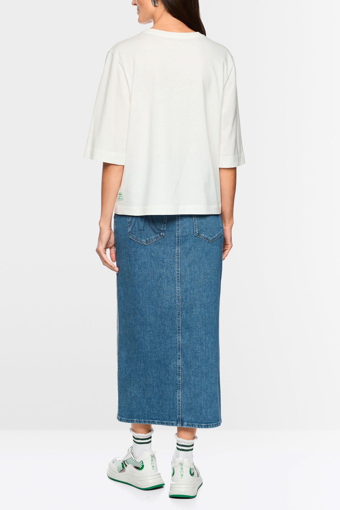 Femme portant un T-shirt imprimée matcha « Rethink Together » vue arrière, associé à une jupe en denim, montrant le style décontracté.