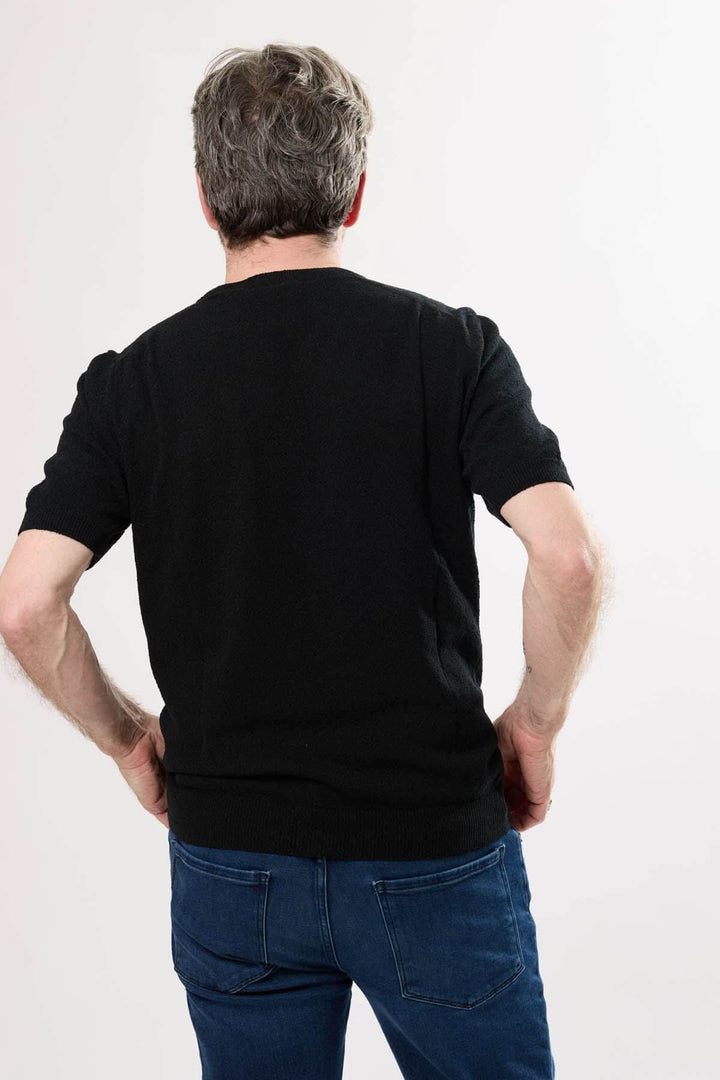 Homme portant un t-shirt élégant noir, vue de dos, avec jean, style décontracté et chic.