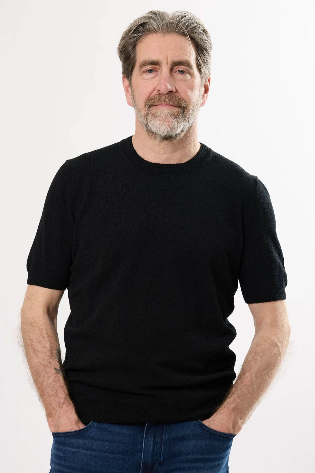 Homme portant un t-shirt noir élégant, alliant confort et style, parfait pour des occasions décontractées ou habillées.