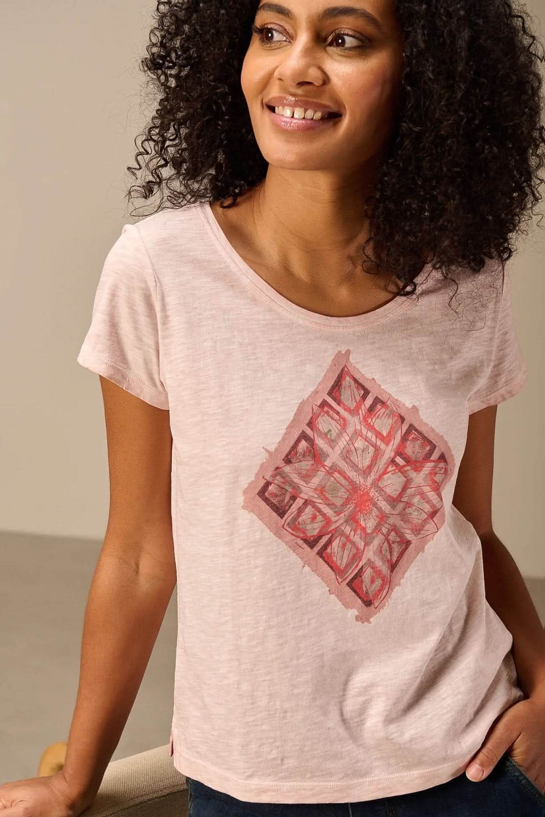T-shirt à manches courtes coupe décontractée rose avec design graphique rouge, porté par une femme souriante, tissu doux et confortable.
