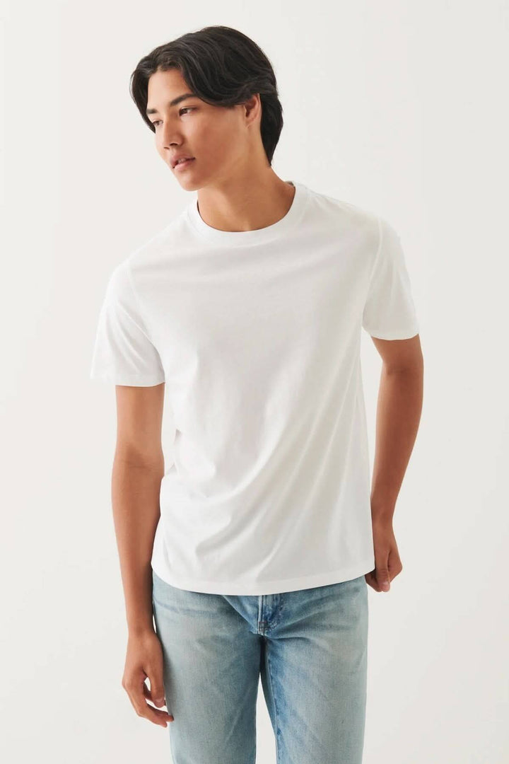 Homme portant un T-shirt minimaliste blanc à col rond, avec un style épuré et une coupe droite.